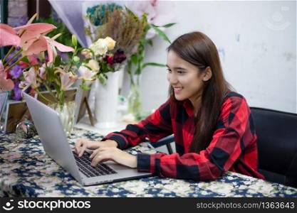 Asian women florists using notebook for working in flower shop