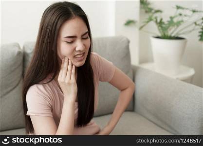 Asian women have toothache pain while sitting on the sofa at home, Asia of girl on the face expression. Concept toothache and dental medicine