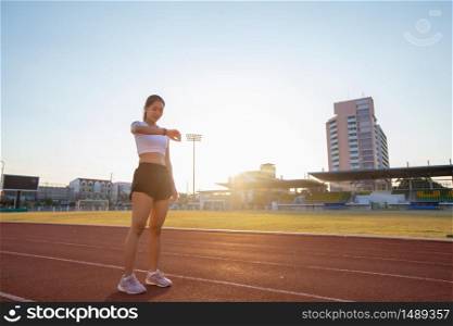 Asian women is watching the sport watch or smart watch for jogging on stadium track -healthy lifestyle and sport concepts