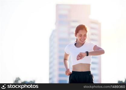 Asian women is watching the sport watch or smart watch for jogging on city