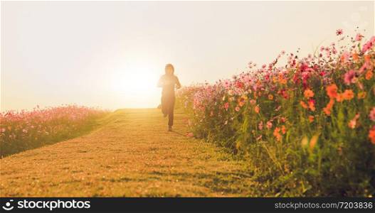 Asian women Jogging on morning at cosmos flower field