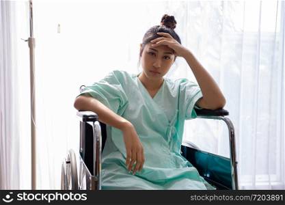 Asian Women patient on wheelchair and she is headache at a hospital
