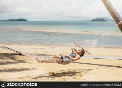 Asian women relaxing in hammock summer holiday on beach