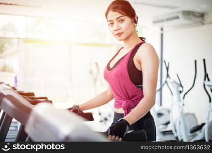 Asian women running sport shoes at the gym while a young caucasian woman is having jogging on the treadmill