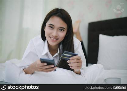 Asian women shopping online and paying with credit card on mobile phone. and Happy women at home surfing the net in bed