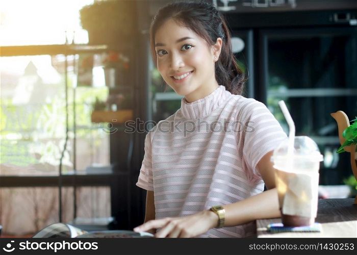 Asian women smiling and reading a book for relaxation at coffee cafe