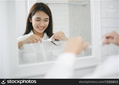 Asian women squeezing toothpaste and brushing their teeth in the bathroom in the morning.