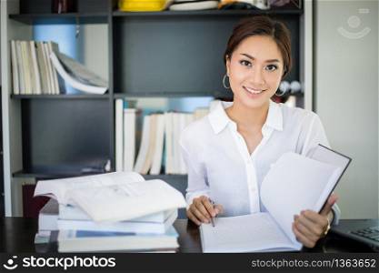 Asian women student smiling and reading a book for final exam at home