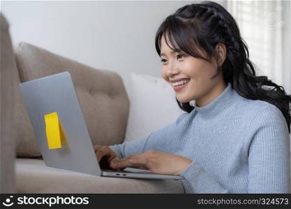Asian women using laptop at home, Asian girl sitting and smiling working at home