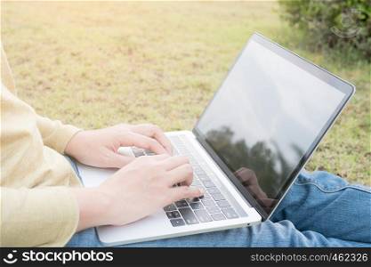 Asian women using laptop on green lawn.