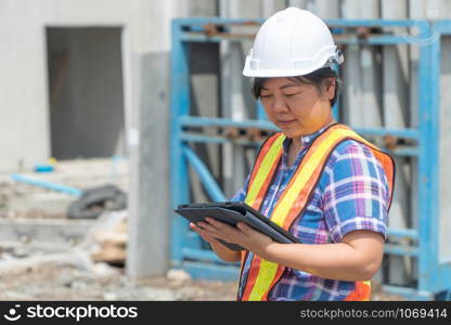 Asian women worker and engineer on building site using tablet for checking the accuracy in places before building and houses.