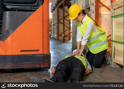 Asian worker do Cardiopulmonary Resuscitation CPR after warehouse manager lying down on warehouse floor after accident from forklift. Using for safety first and business insurance concept.