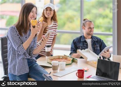 Asian worker with casual suit talking and eatting with happy action when lunch time in the creative office workplace, lifestyle and relax work concept