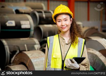 Asian worker woman with safety vest holding tablet computer walking to checking warehouse storage in factory, Professional engineer checking machine walk at roofing metal sheet storage industrial