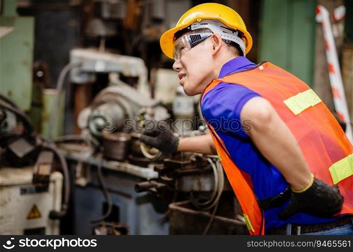 Asian worker working hard in industrial factories suffer from back waist pain while working on machines.