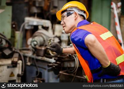 Asian worker working hard in industrial factories suffer from back waist pain while working on machines.