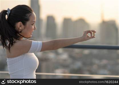 Asian working woman in casual suit holding bitcoin over the cityscape blurred background, business and cryptocurrency concept