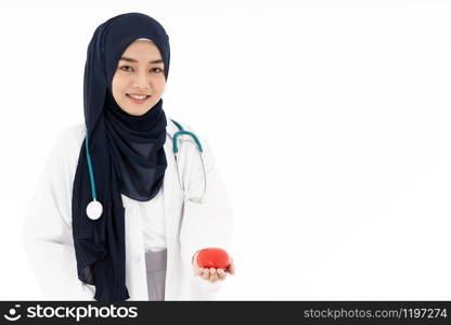 Asian young adult attractive muslim woman doctor wearing hijab standing with stethoscope and holding red heart isolated in white background. Healthcare medical and insurance concept.