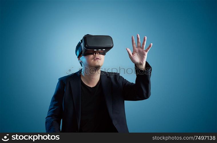 Asian young amazed businessman wearing virtual reality headset isolated on gradient blue background .Future multimedia visual effects technology concept .