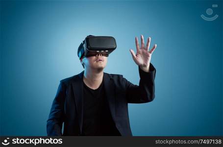 Asian young amazed businessman wearing virtual reality headset isolated on gradient blue background .Future multimedia visual effects technology concept .
