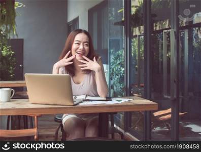 Asian young beautiful woman laughing while working with happiness and sitting in coffee shop