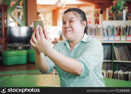 Asian young blind woman disabled person taking selfie or video call using smart phone in creative workplace