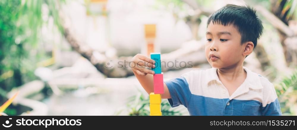 Asian young boy playing wooden block toy on table for creative and development, happy child learn skill for activity puzzle and creativity for game at home, education concept, banner website.