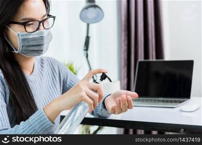 Asian young business beautiful woman wearing face mask protective working from home office with laptop computer desk he quarantines disease coronavirus and cleaning hands by sanitizer alcohol gel pump