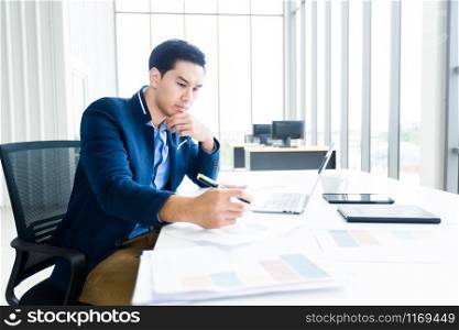 asian young businessman have ideas make a note business plan of notebook and laptop computer on wooden table background in office.