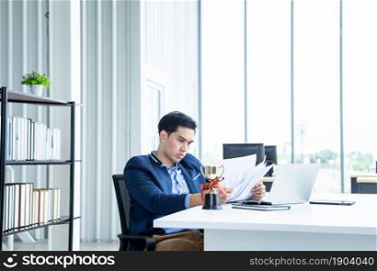 asian young businessman have stressed see a the document business plan and laptop computer on wooden table In the office room background.