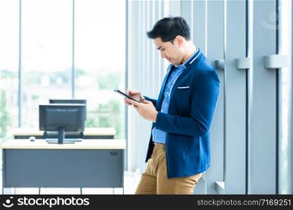 asian young businessman working with hand smartphone In the office room background.