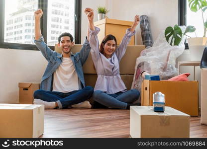 Asian young couple are glad after successfull packing the big cardboard box for moving in new place, Moving and House Hunting concept,