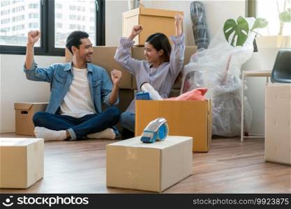 Asian young couple are glad after successfull packing the big cardboard box for moving in new house, Moving and House Hunting concept,