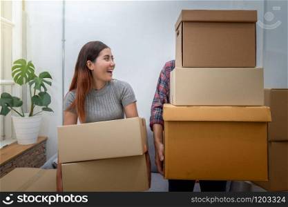 Asian young couple carrying big cardboard box for moving in new house, Moving and House Hunting concept