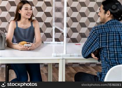 Asian young couple eating out together at new normal social distance restaurant with table shiled partition reduce infection of coronavirus covid-19 pandemic. Restaurant new normal lifestyle.