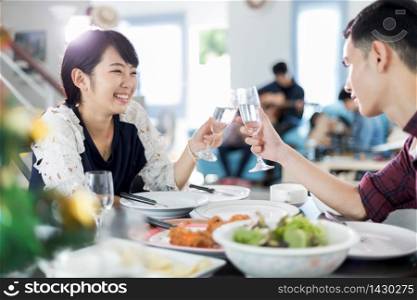 Asian young couple enjoying a romantic dinner evening drinks while sitting at the dinning table on the kitchen together