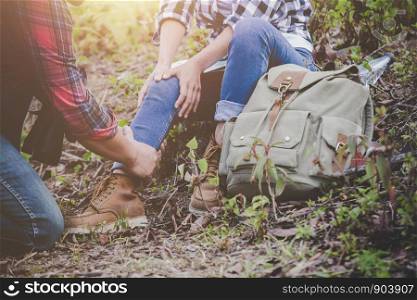 Asian young couple travelers to hiking ankle injury on a green background, Hiking concept.