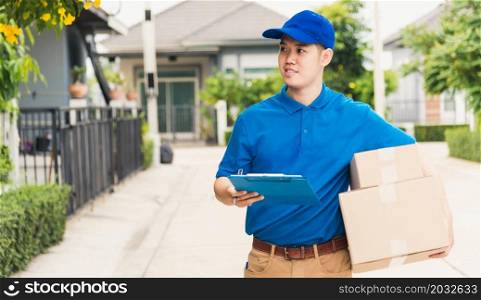 Asian young delivery man courier in uniform hold parcel post boxes service shipment and walking finding and looking for customer home location, Online shopping service concepts