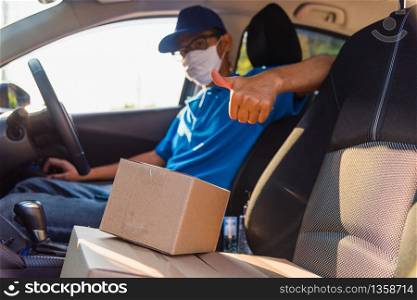 Asian Young delivery man courier online with boxes with uniform sitting in driving car he protective face mask, service customer on front house under curfew quarantine pandemic coronavirus COVID-19