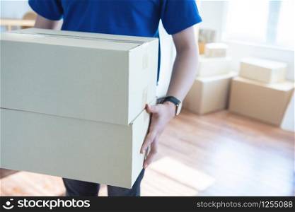 Asian young delivery man holding and carrying two cardbox standing in workplace.