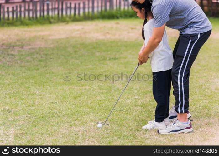 Asian young father support teaching training daughter to play perfect golf while standing in the game of golf together in nature a field garden park, family outdoors sport concept