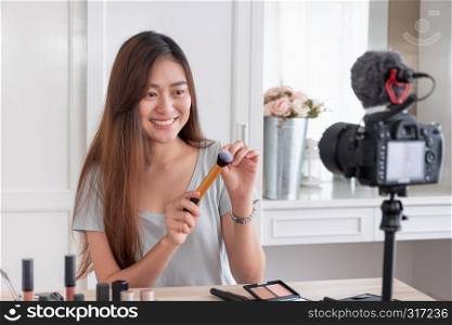 Asian young female blogger recording vlog video with makeup cosmetic at home online influencer on social media concept.live streaming viral