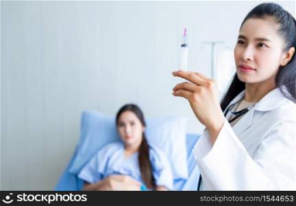 Asian young female doctor with syringe to Asian young female patient on Bed for better healing In the room hospital background.