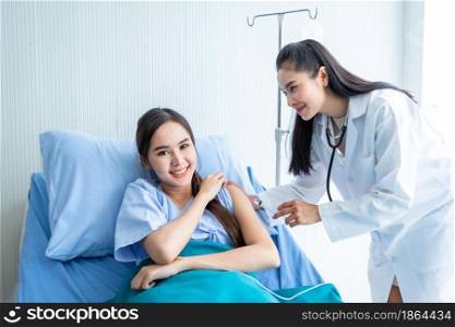 Asian young female doctor with syringe to the arm of Asian young female patient on Bed for better healing In the room hospital background.