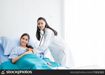 Asian young female patient on bed while doctor hands of checking examining his pulse for record the treatment results with smiley face very good symptom in hospital background.