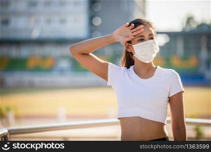 Asian Young fitness sport woman is resting tired and she wears a mask for protective Dust and pollution on city