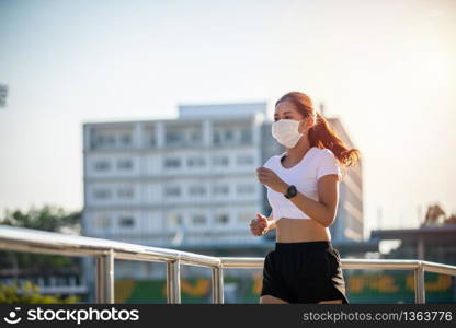 Asian Young fitness sport woman running and she wears a mask for protective Dust and pollution on city