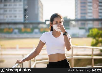 Asian Young fitness sport woman running and she wears a mask for protective Dust and pollution on city