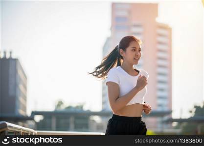 Asian Young fitness sport woman running and smiling on city road
