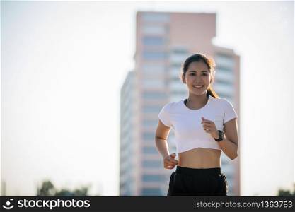 Asian Young fitness sport woman running and smiling on city road